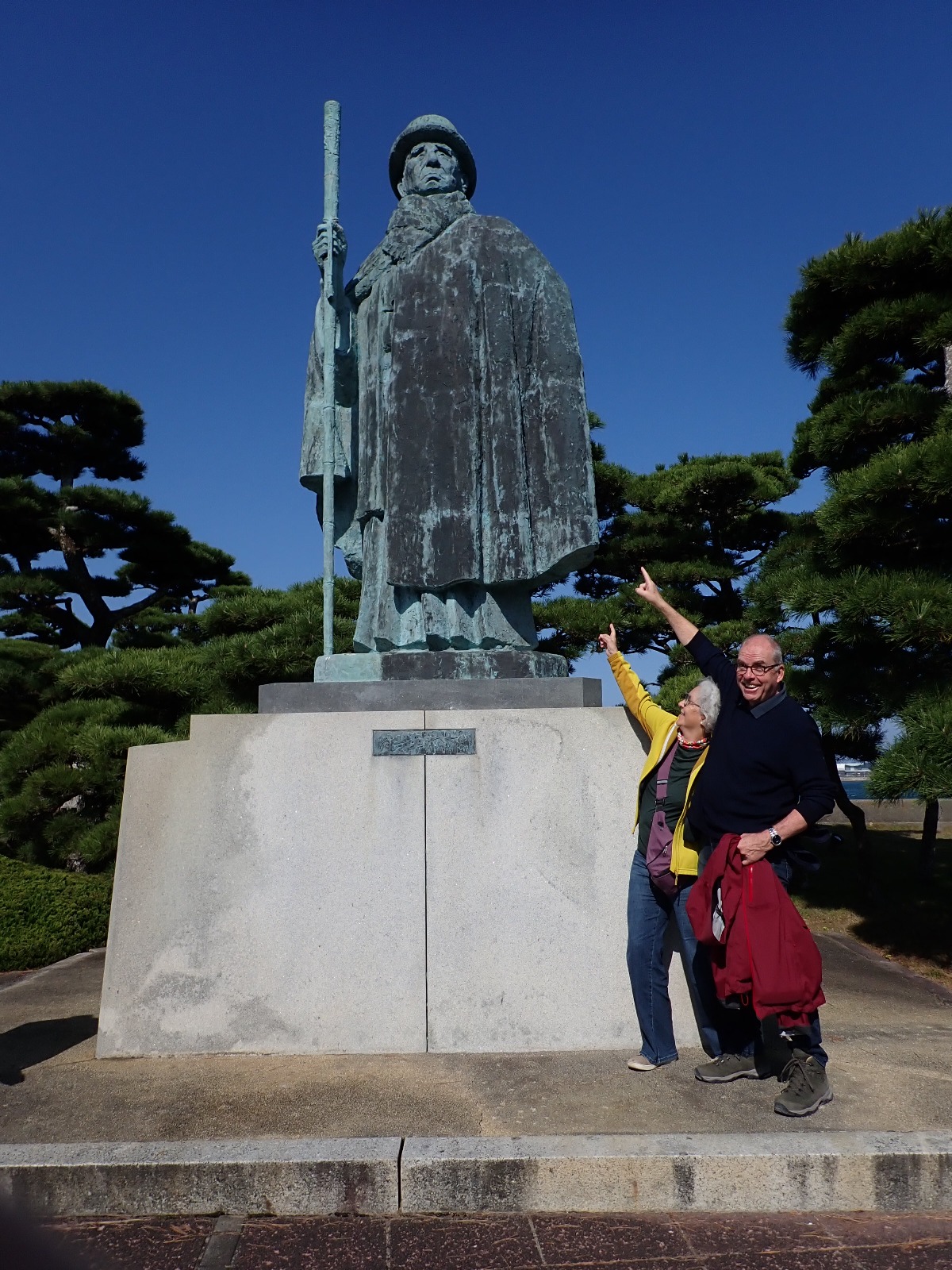 御木本幸吉像の前でポーズをとる男女